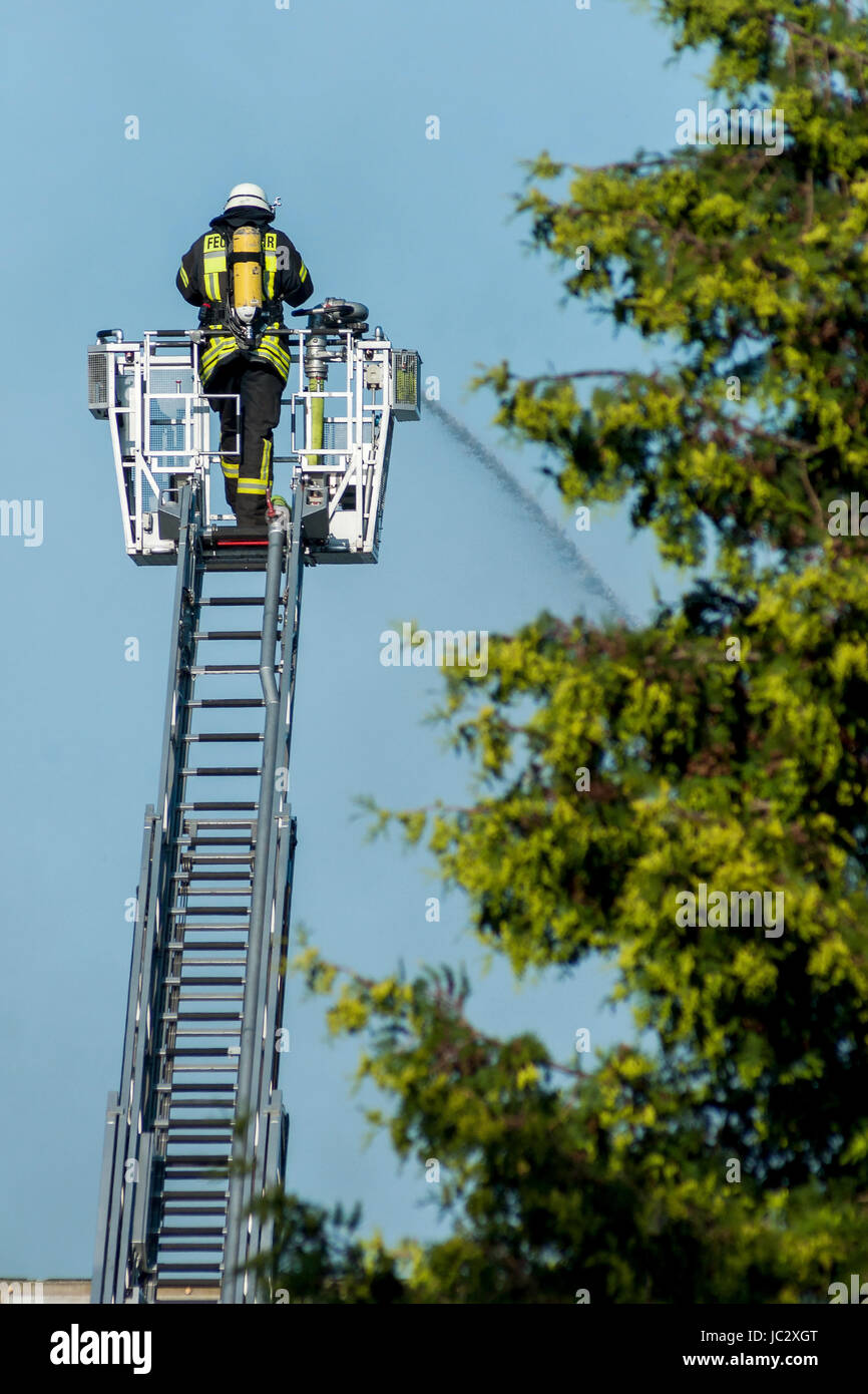 Feuerwehrmann beim Feuerlöschen von der großen Leiter aus Stock Photo