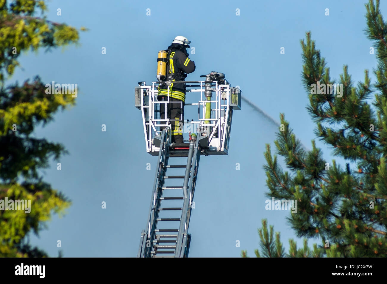 Feuerwehrmann beim Feuerlöschen von der großen Leiter aus Stock Photo