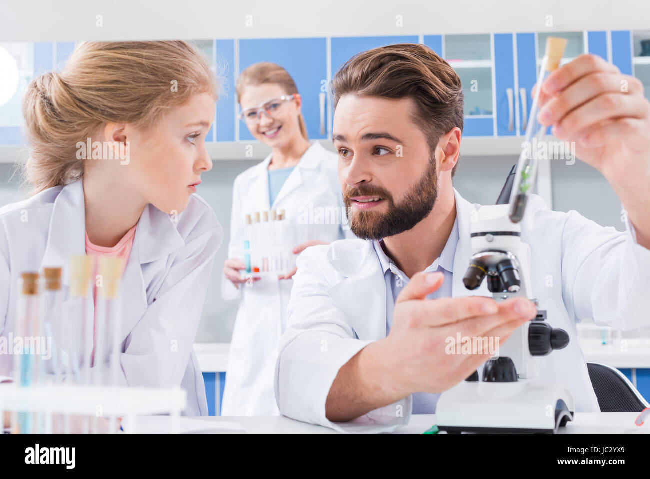 Smiling bearded teacher and serious little student making experiment in lab Stock Photo