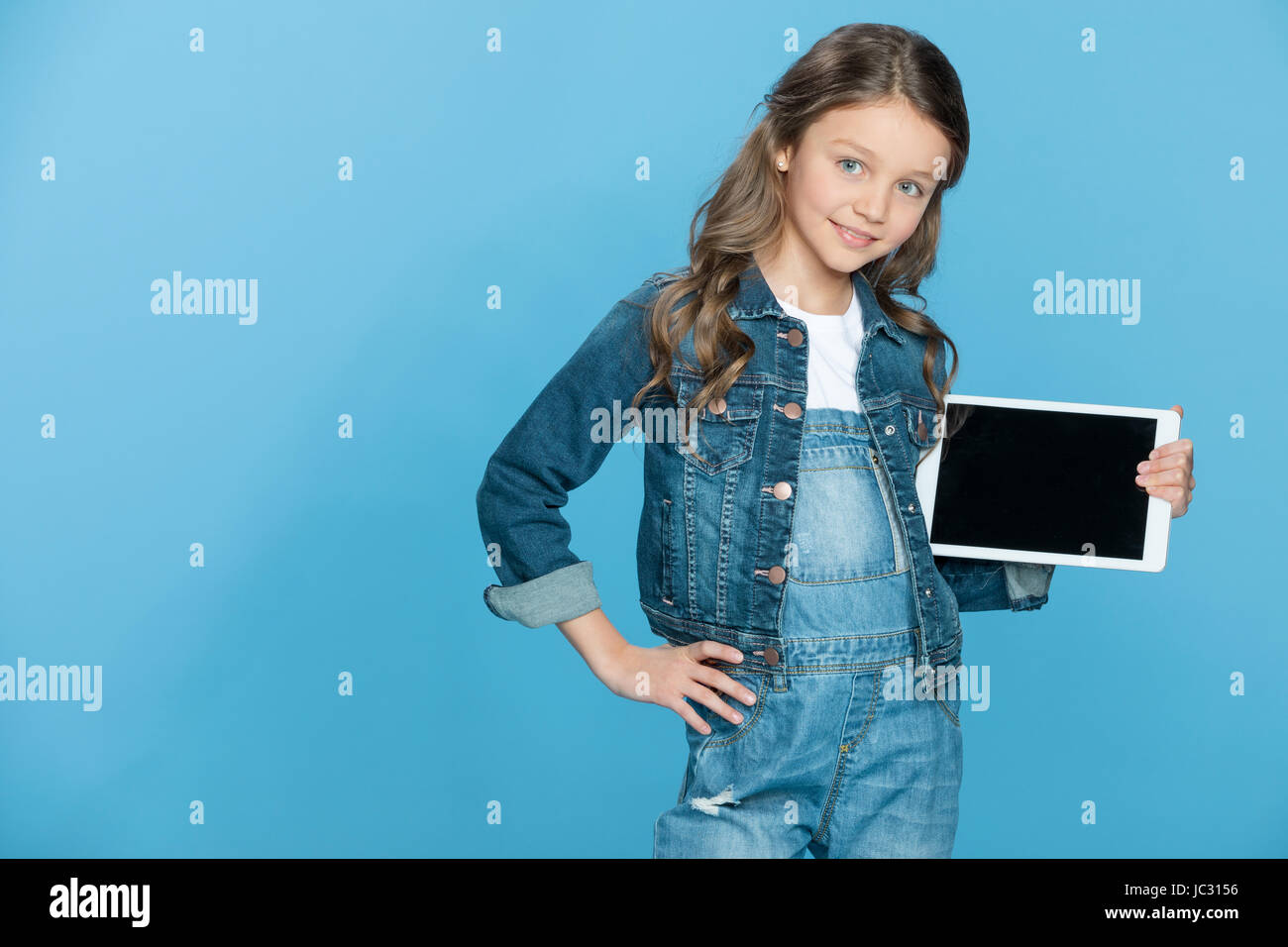 Cute smiling little girl holding digital tablet with blank screen on blue  Stock Photo - Alamy