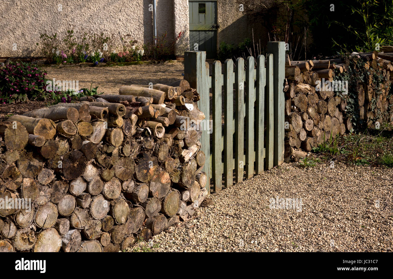 front gate to house with wood logs used as fence,English garden,England Stock Photo