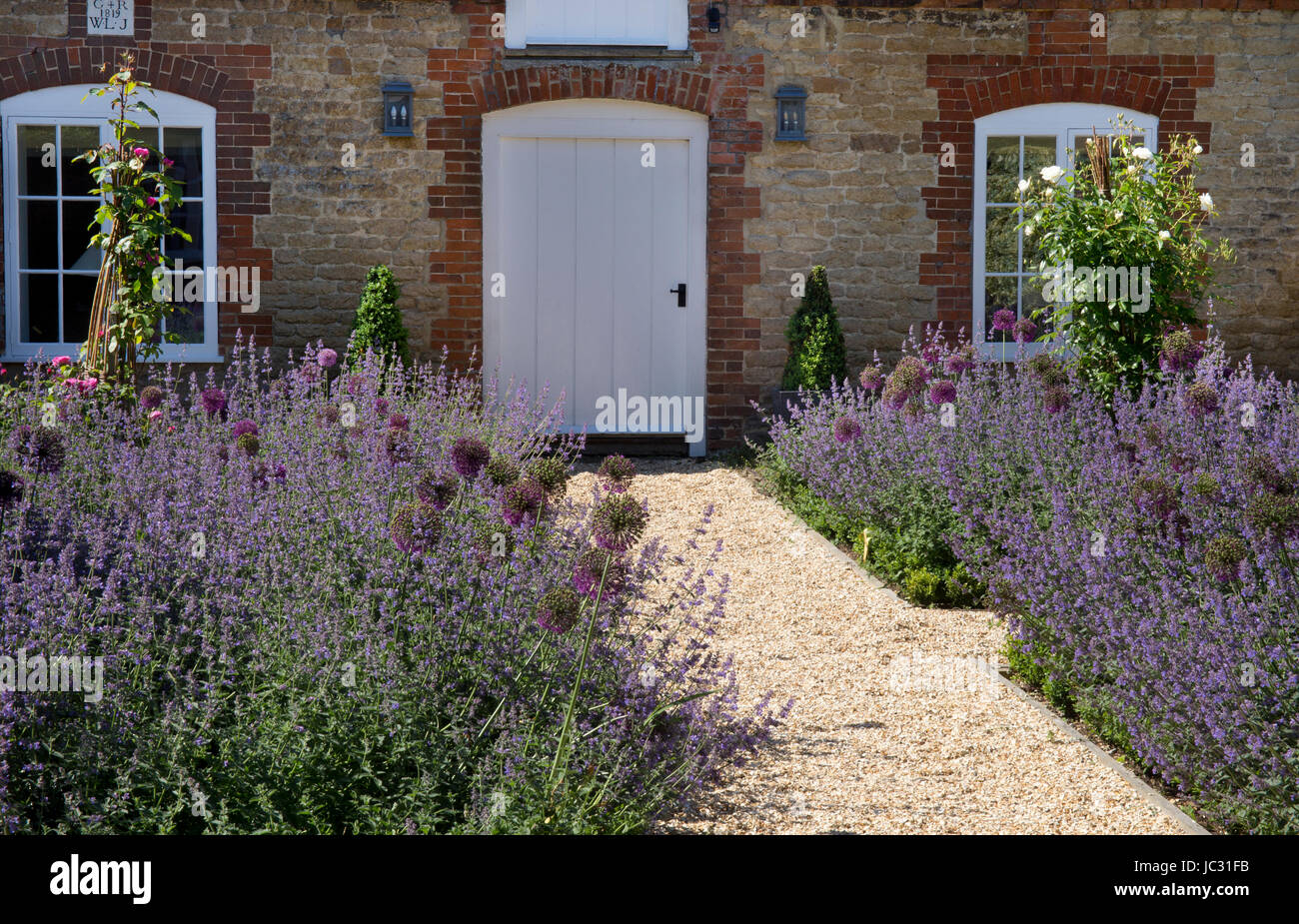 gravel path with boarders of summer flowers in english garden Stock Photo