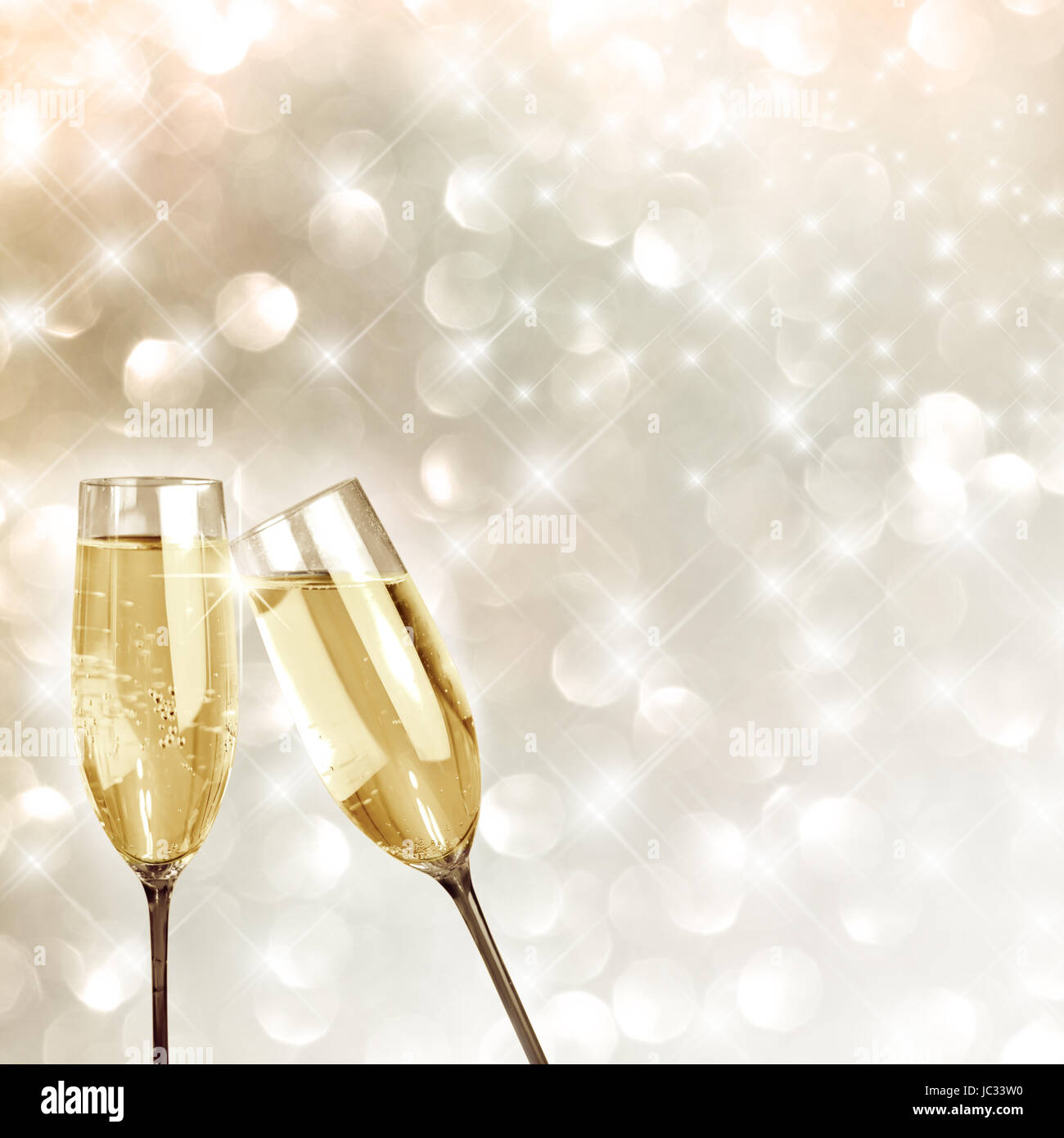 Champagne toast. Two filled champagne flutes touch in a spill over