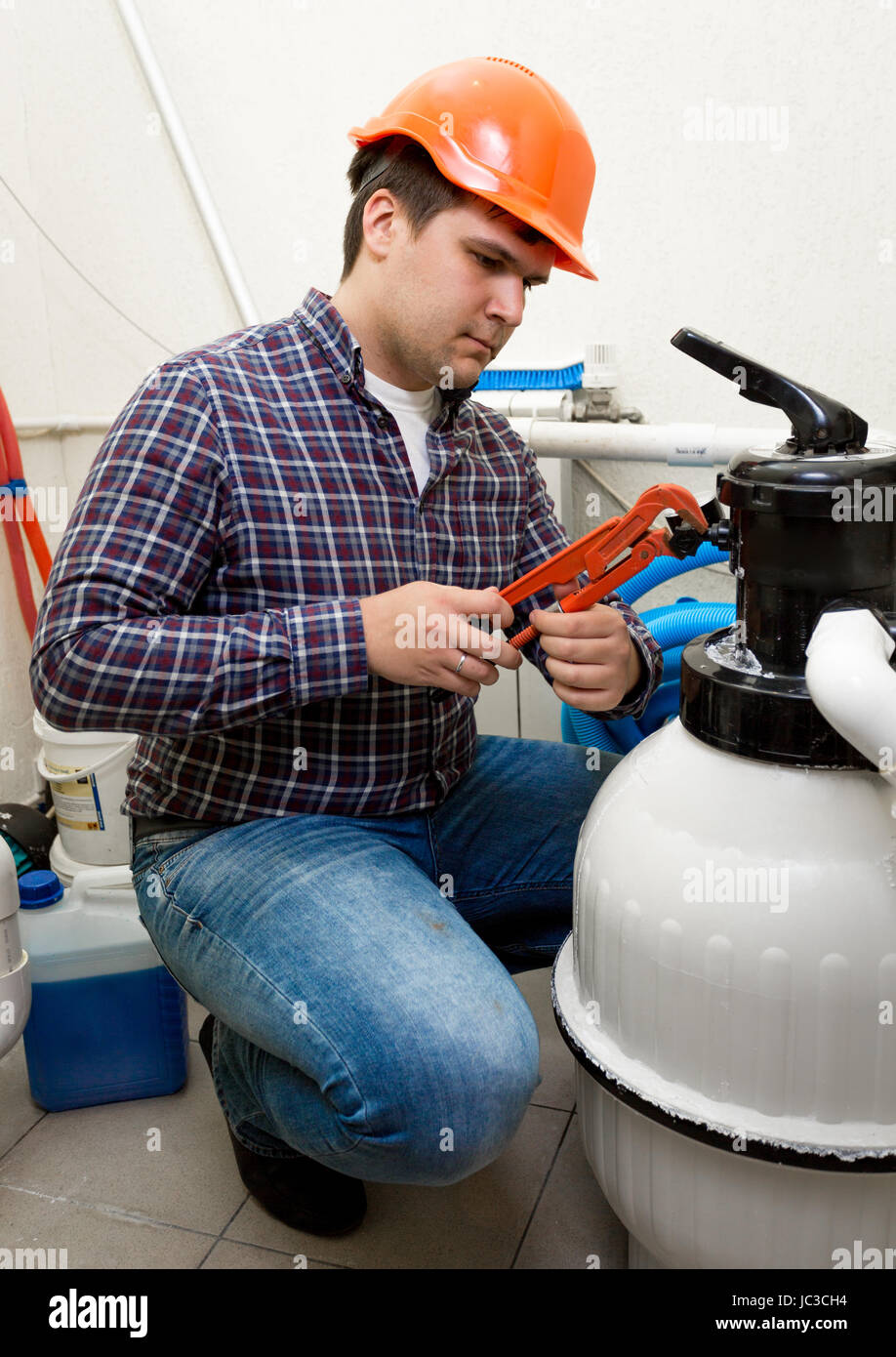 Young plumber installing manometer on high pressure barrel Stock Photo