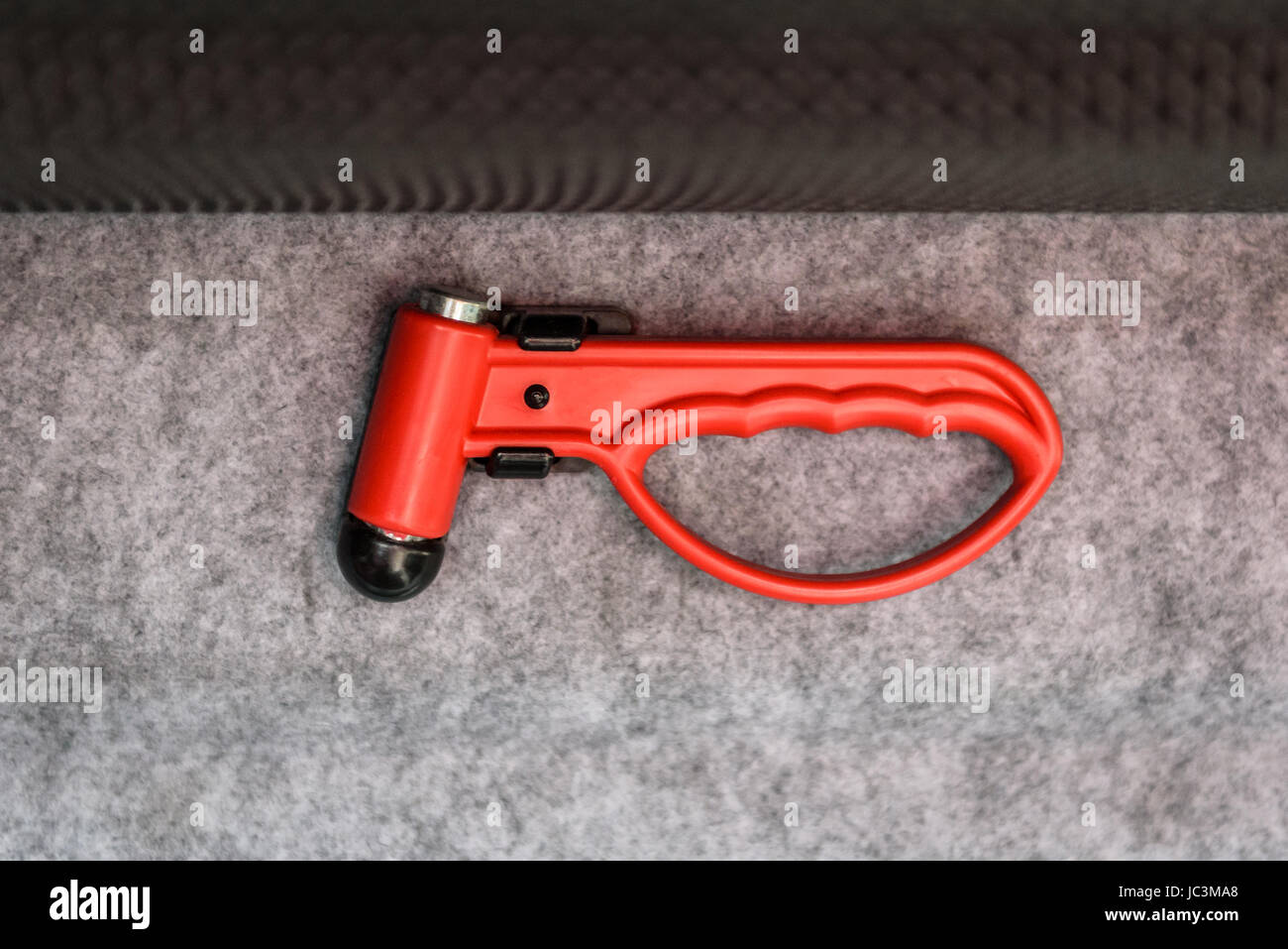 Red evacuation emergency break glass hammer tool on public transport. Emergency tool for breaking glass or cutting safety belts in case of accident on Stock Photo