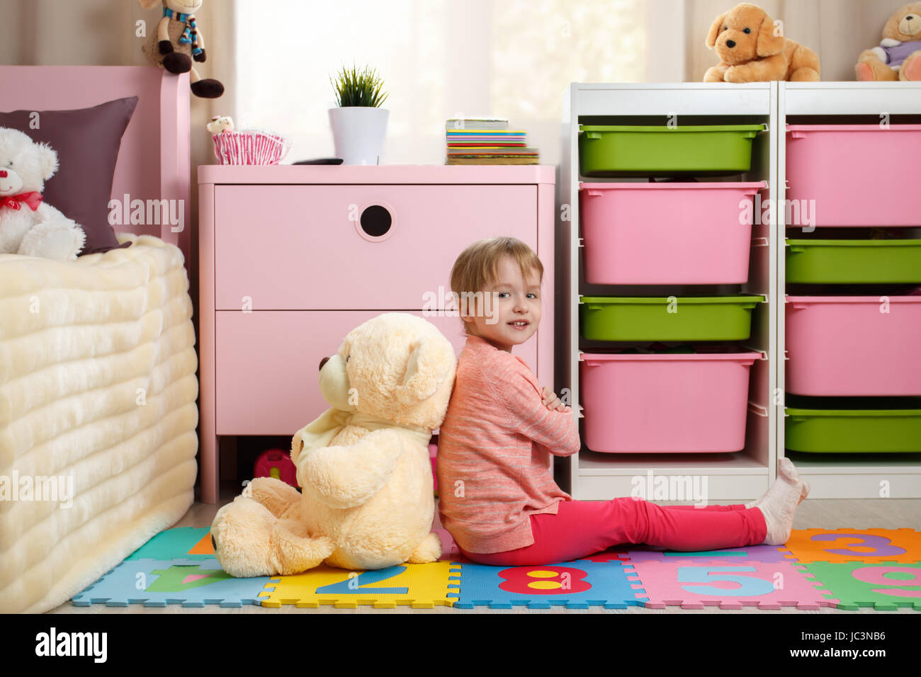 Cute little girl with a big teddy bear sitting on the floor in the ...