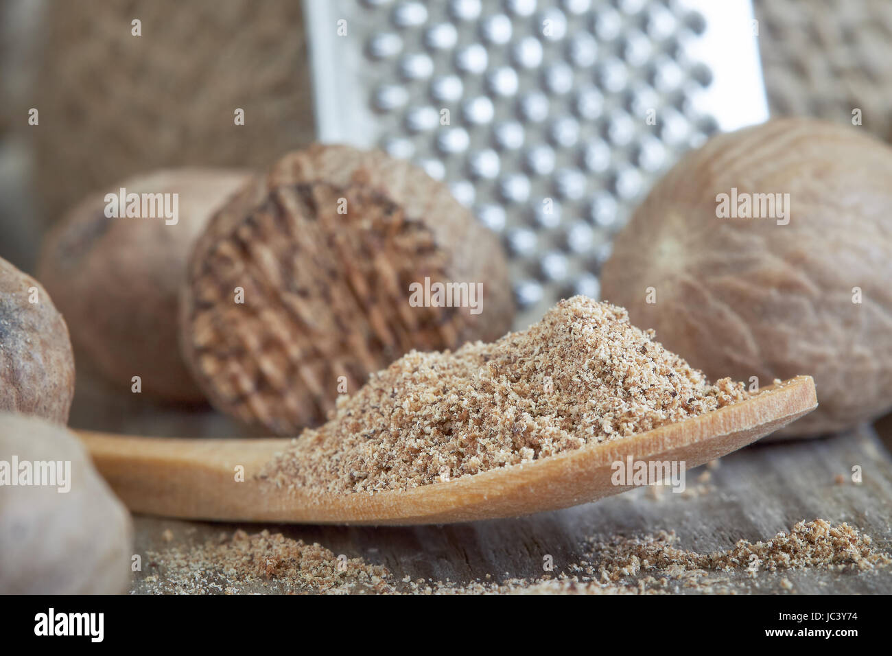 Group of nutmeg seeds with nutmeg powder in wooden spoon Stock Photo