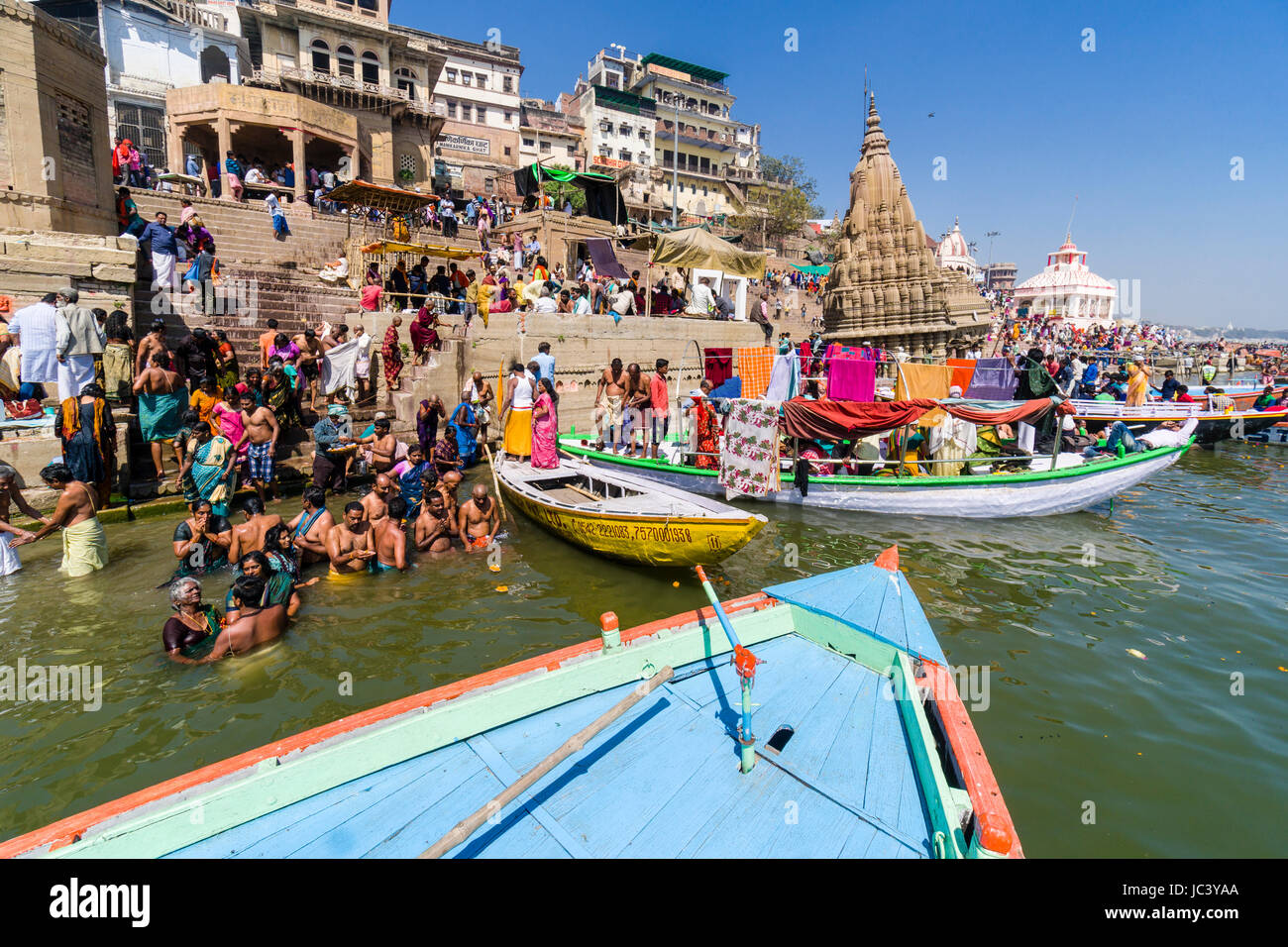 Pilgrims are taking bath in the holy river Ganges at Manikarnika Ghat in the suburb Godowlia Stock Photo