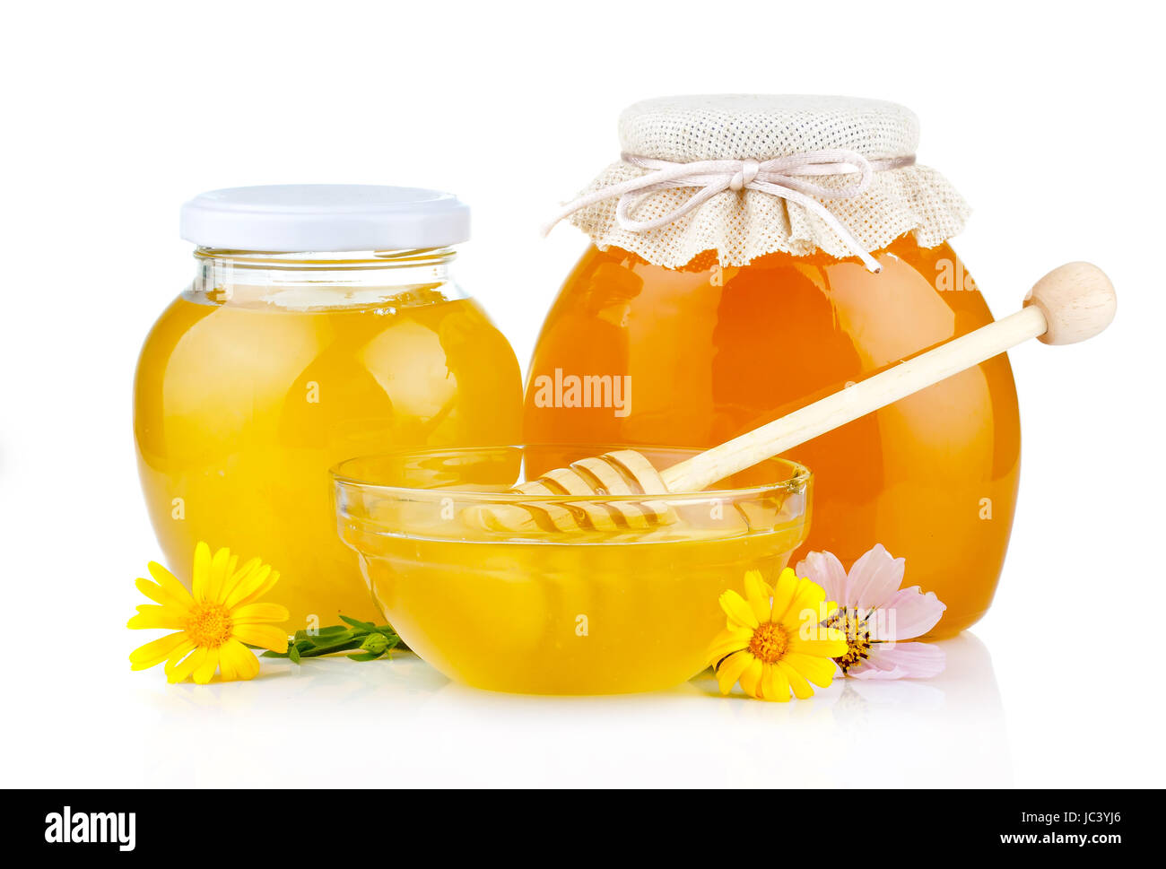 Sweet honey in glass jars with flowers and dipper isolated on white background Stock Photo