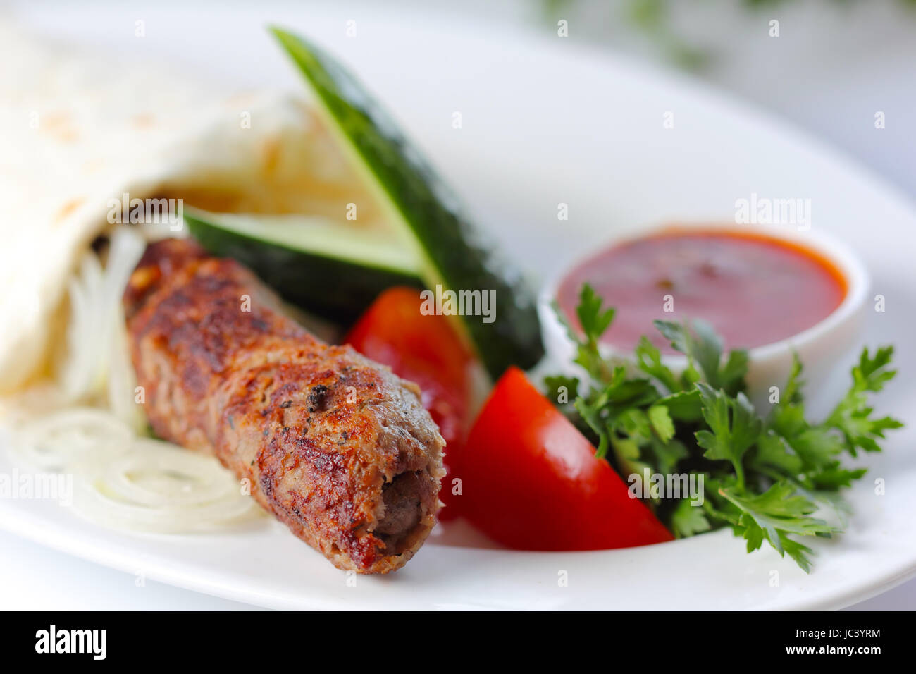 shish pork kebab with greens and vegetables (closeup, selective focus) Stock Photo