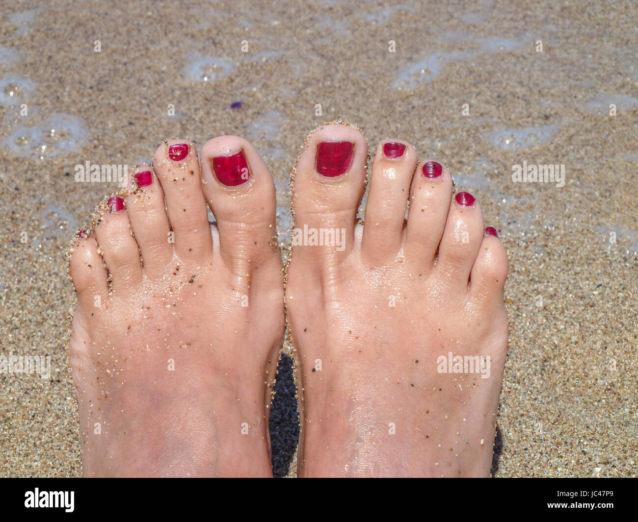 Photo of beautiful female feet with red pedicure in the sand on the ...