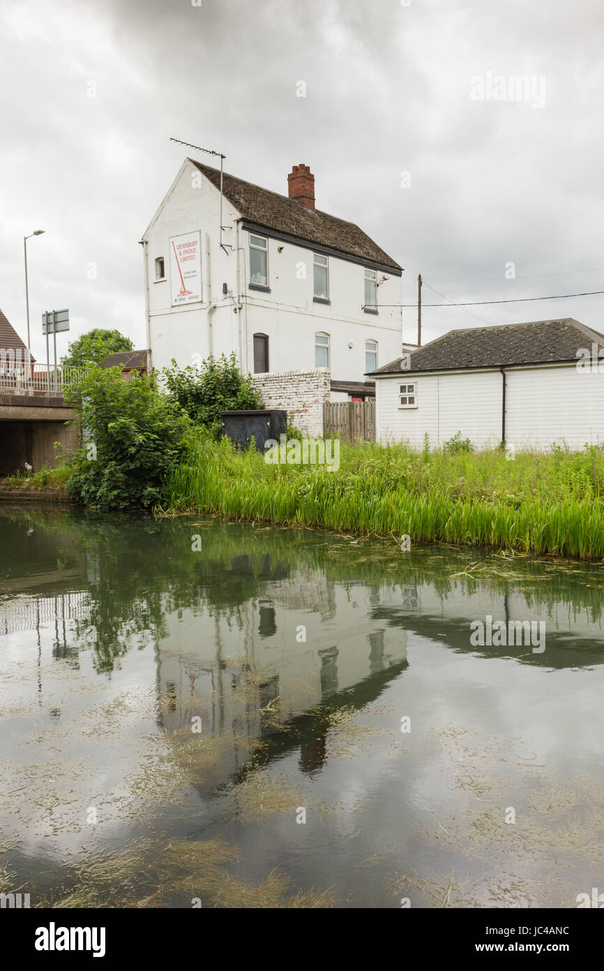 White commercial or industrial building reflected in the Birmingham to Wolverhampton canal at Coseley, Black country west midlands Stock Photo