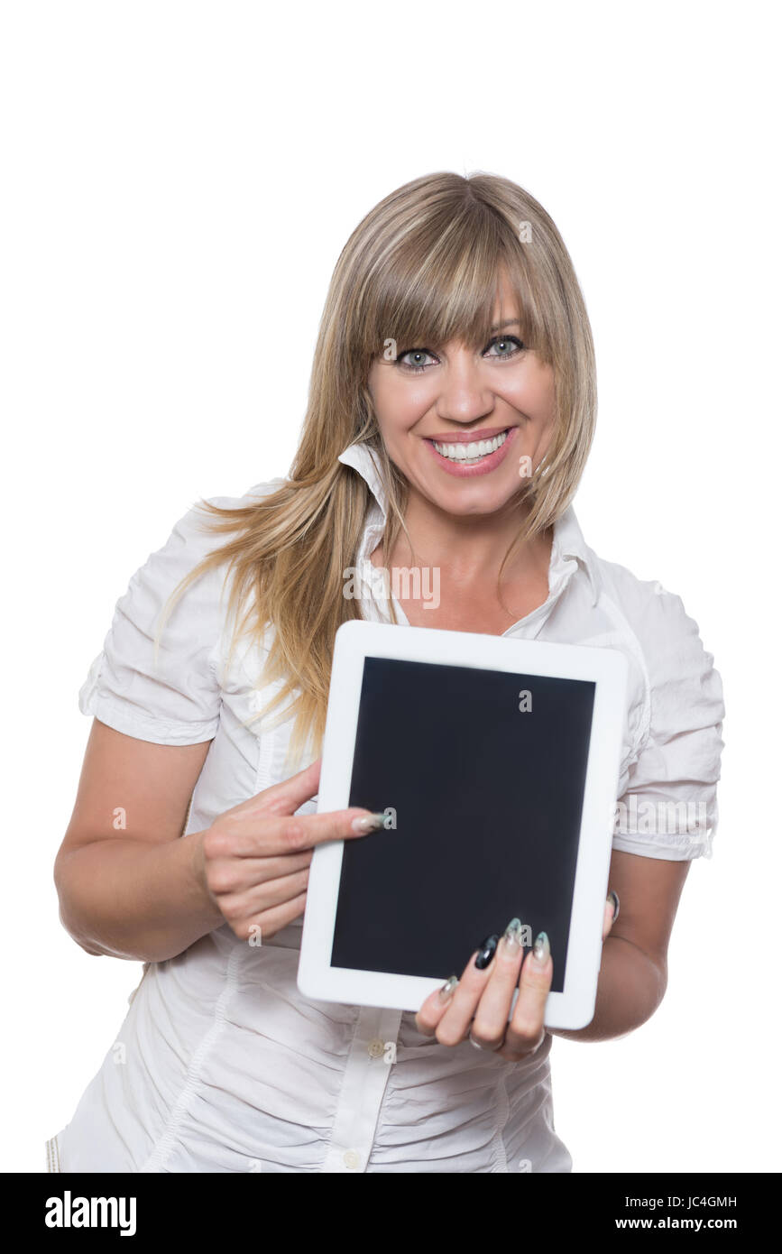 Freigestelltes Foto einer lächelnden Frau, die mit ihrem Finger auf ein Tablet zeigt. Die Frau schaut zur Kamera. Stock Photo