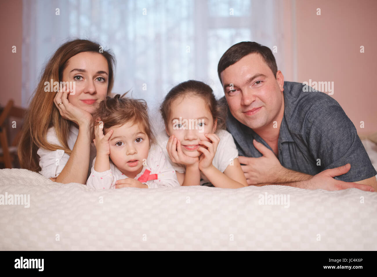 young family lying in bed at home Stock Photo