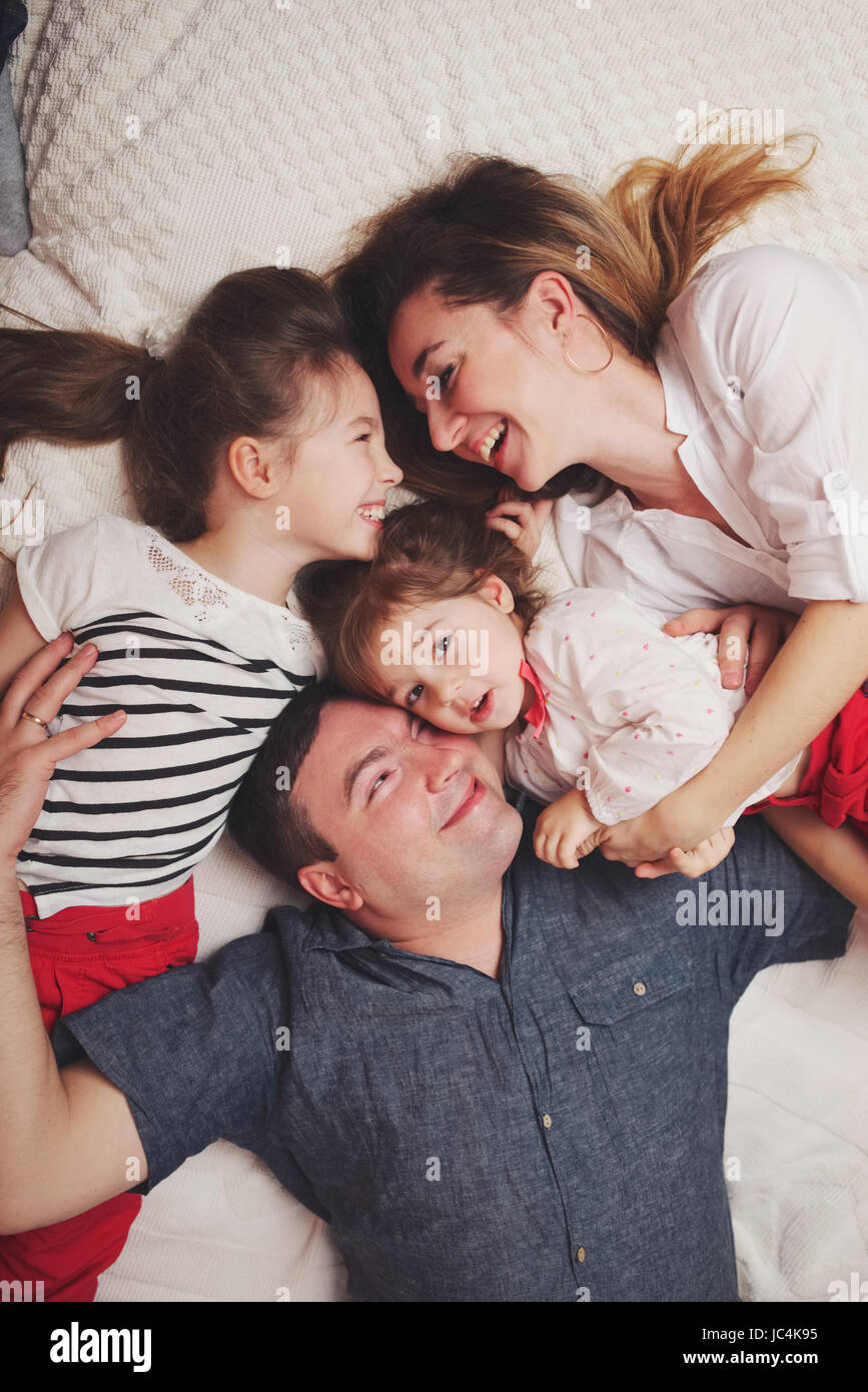young family lying in bed at home Stock Photo