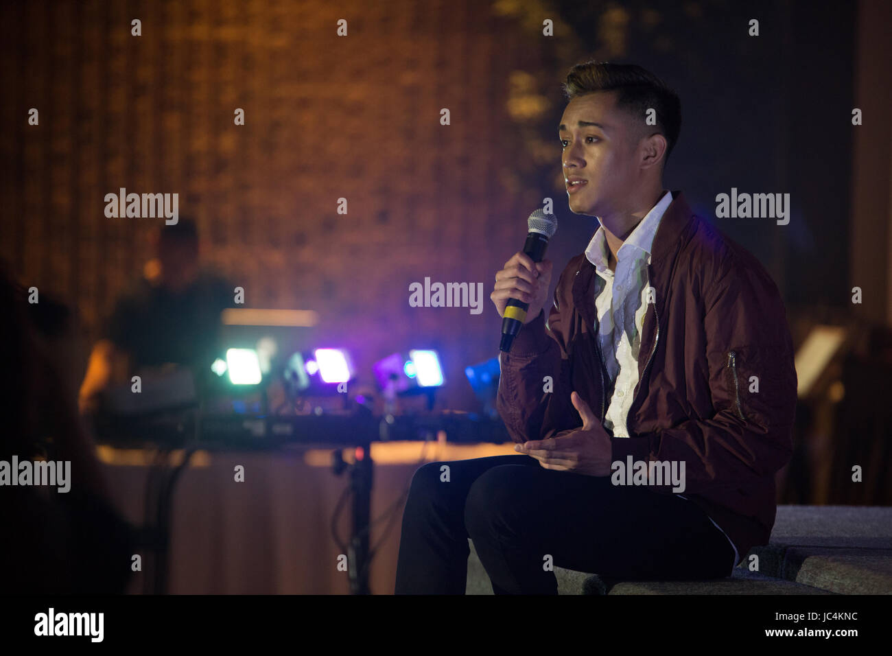 A young Asian man singing and performing indoor Stock Photo