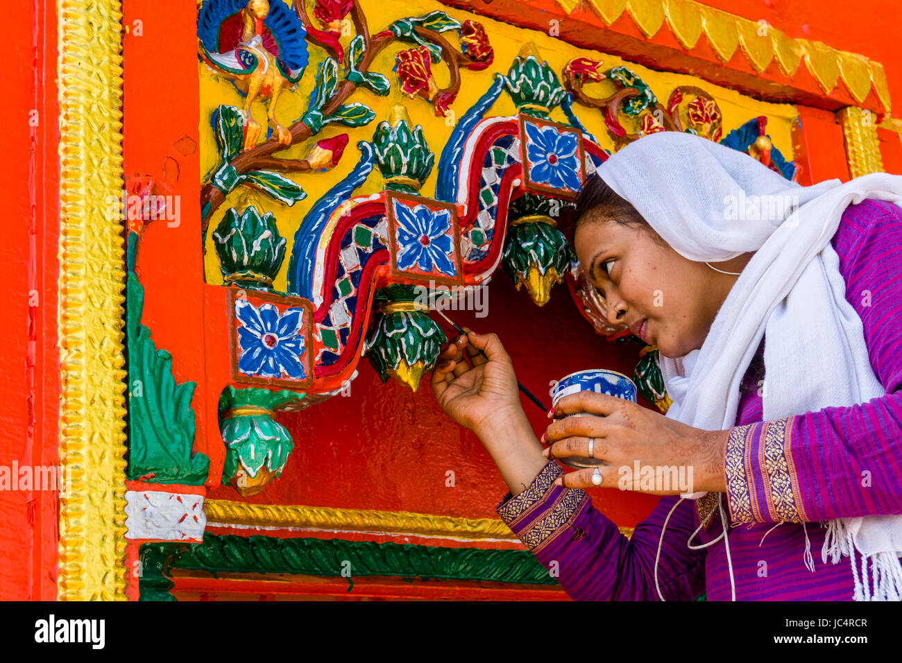 A woman is painting a colorful small hindu temple in the suburb Godowlia Stock Photo