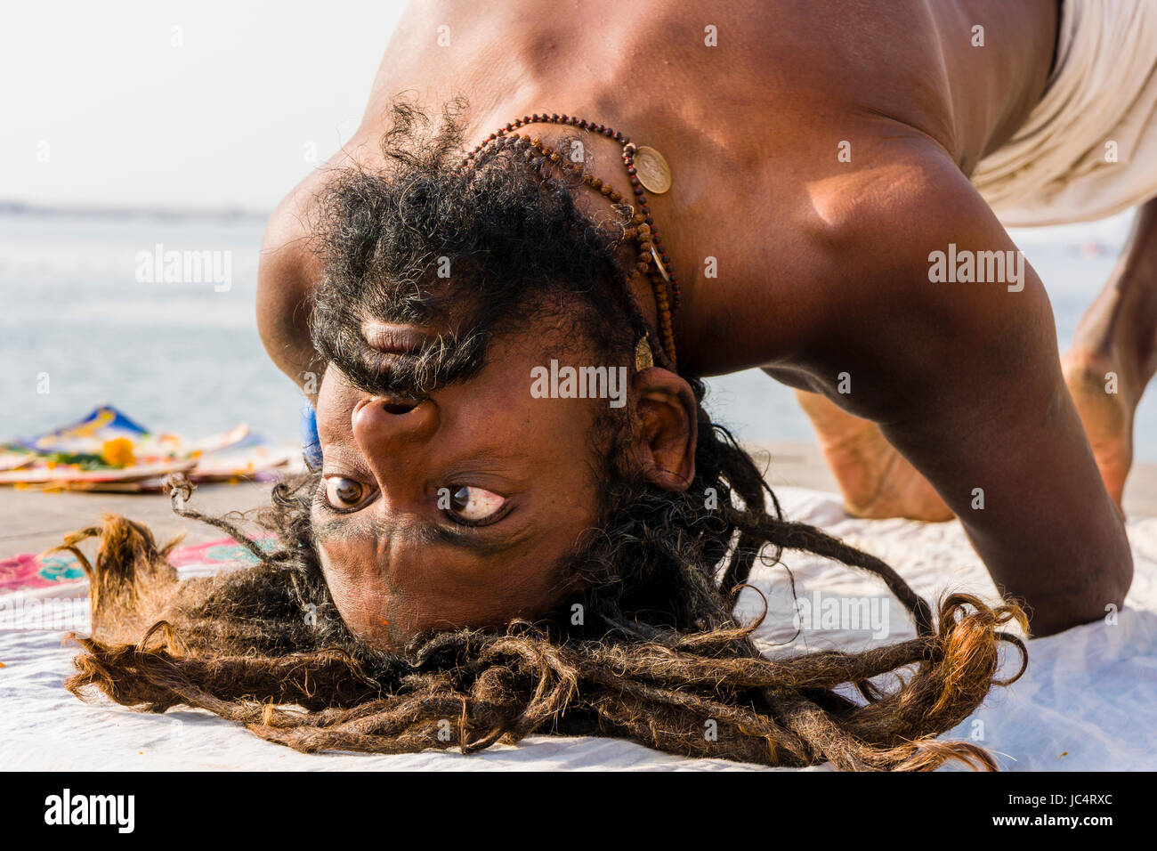 A Sadhu, holy man, is practising eye yoga asana on a platform at the holy river Ganges at Meer Ghat in the suburb Godowlia Stock Photo