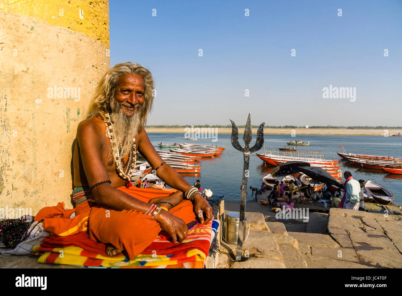 A Sadhu, holy man, is sitting on a platform at the holy river Ganges at Dashashwamedh Ghat, Main Ghat, in the suburb Godowlia Stock Photo