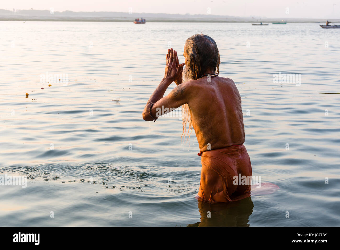 A Sadhu, holy man, is standing in the water of the holy river Ganges and praying at Lalita Ghat in the suburb Godowlia Stock Photo