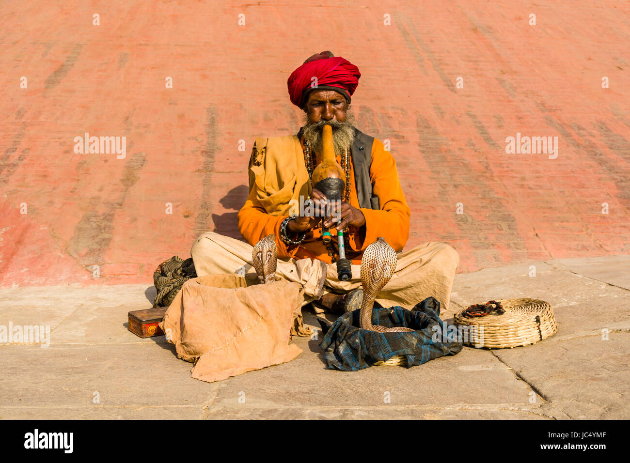 A snake charmer is playing flute to get his cobra dancing at the holy river Ganges at Dashashwamedh Ghat, Main Ghat, in the suburb Godowlia Stock Photo