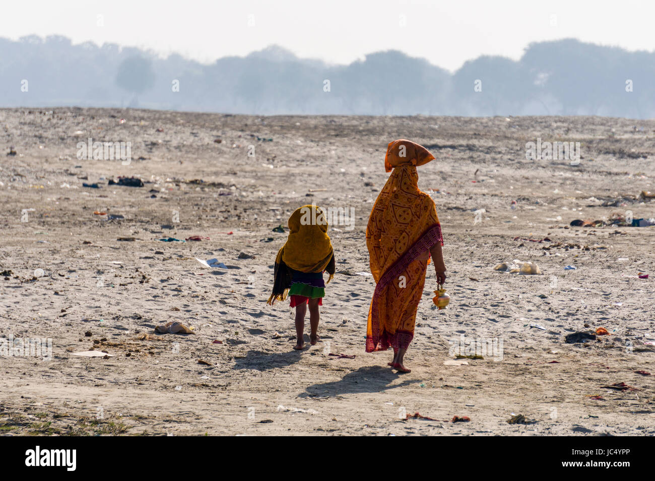 A woman and her child are walking on the sand banks at the holy river Ganges Stock Photo