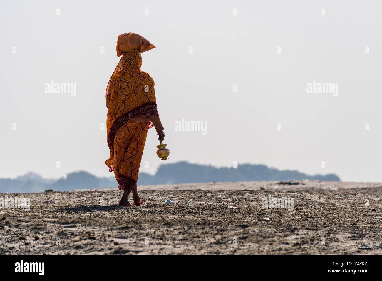A woman is walking on the sand banks at the holy river Ganges Stock Photo
