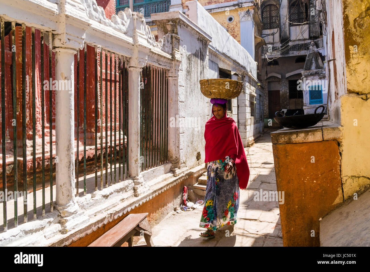 A woman, carrying a basket on her head and selling goods, is walking in the streets of the suburb Godowlia Stock Photo