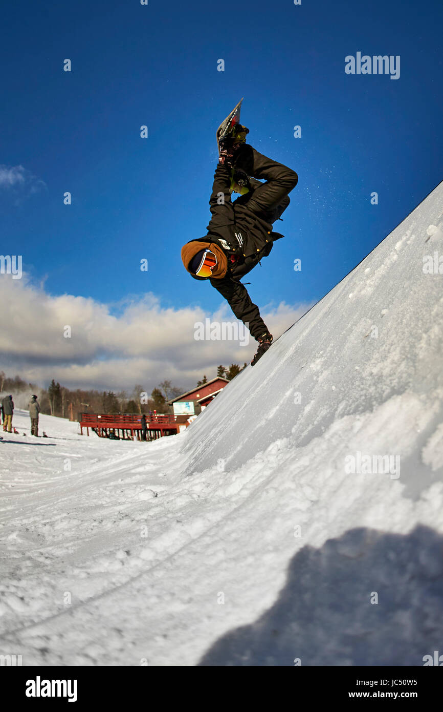 A snowboarder doing a handplant on a feature in the terrain park. Stock Photo