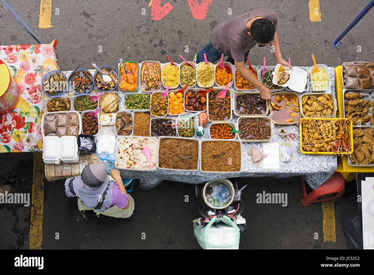 KOTA KINABALU, MALAYSIA - JUNE 10, 2017: Top view of customer buying from vendor owner selling variety of cakes and dessert during Ramadan bazaar. Stock Photo