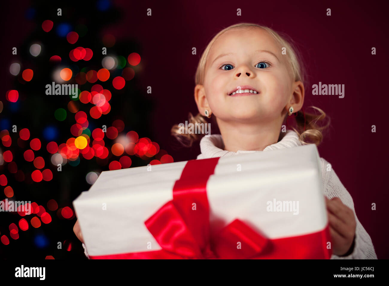 Happy little girl at christmas time holding her present Stock Photo - Alamy
