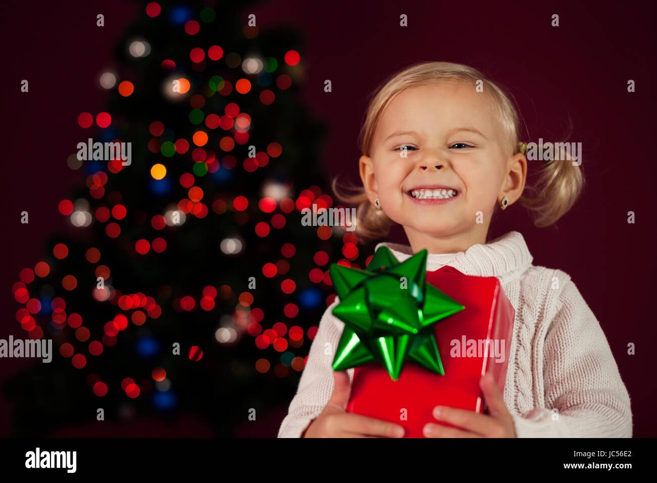 Cute little girl holding christmas gift Stock Photo - Alamy