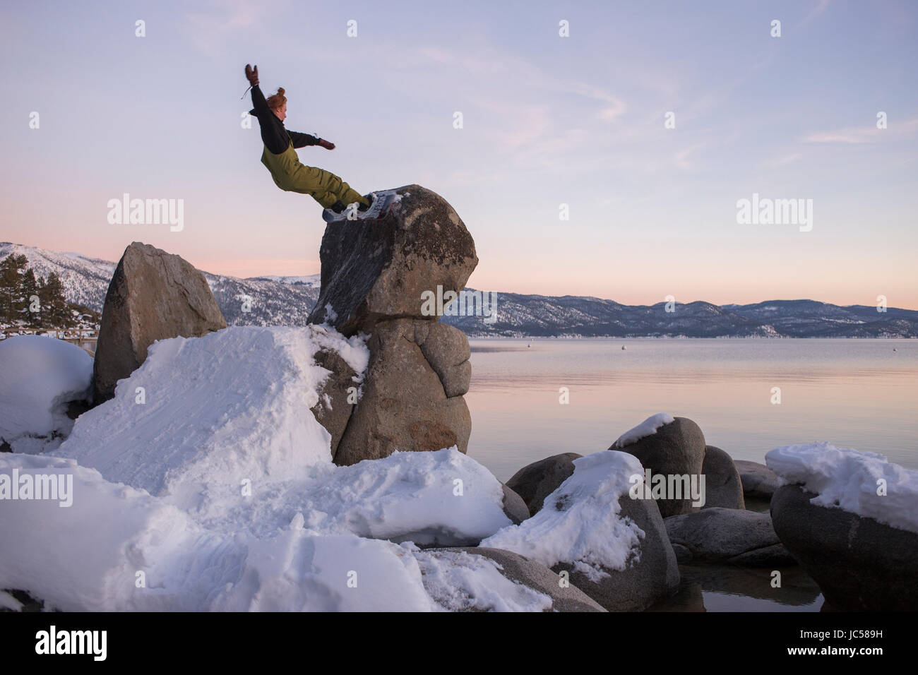 Snowboarder creates a jump at a granite boulder on Tahoe's north shore