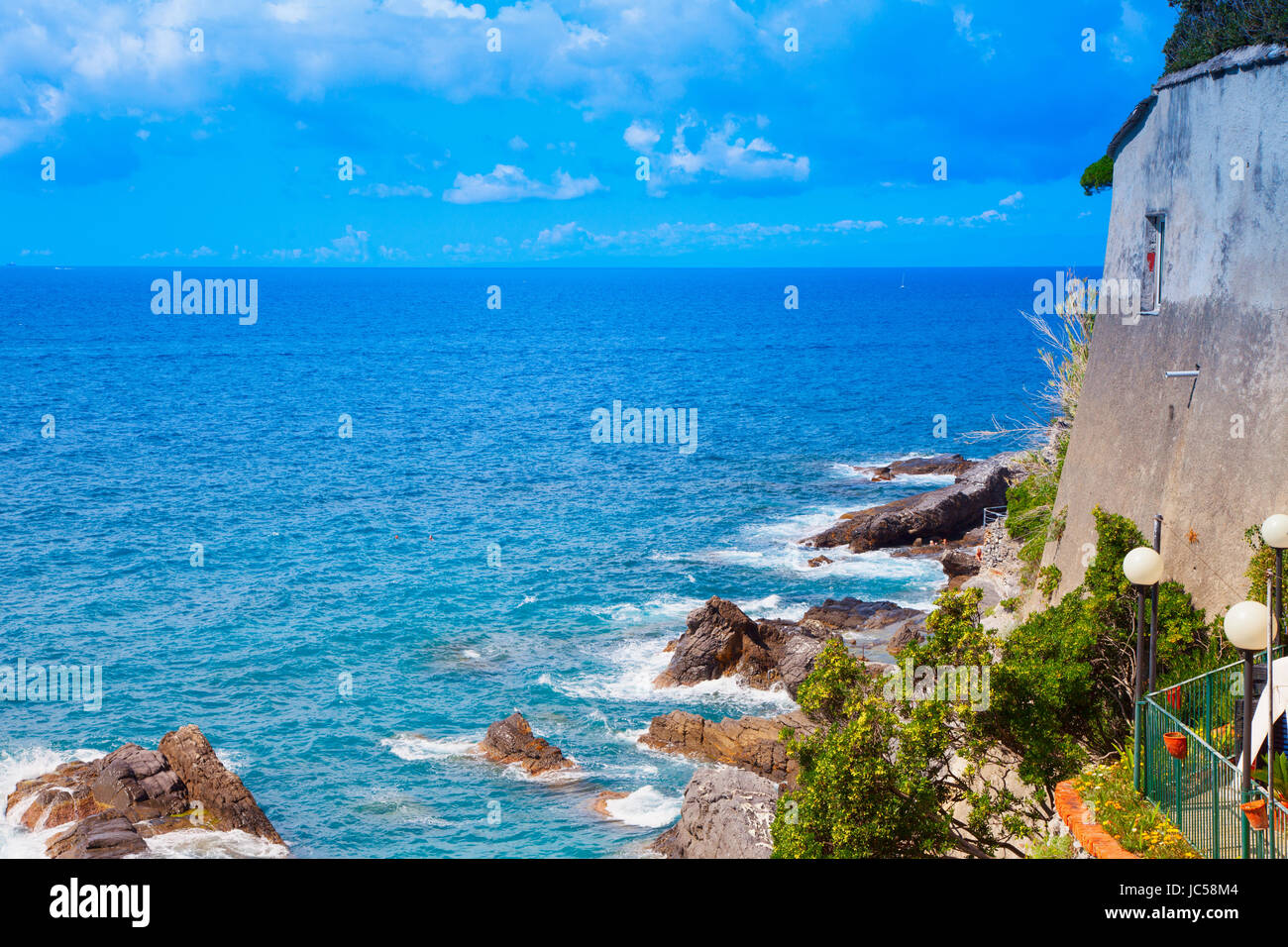 Sea with building on the right, rocks and foam Stock Photo - Alamy