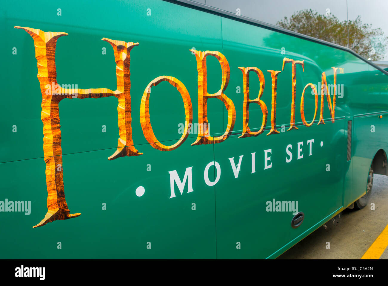 NORTH ISLAND, NEW ZEALAND- MAY 16, 2017: A full bus of tourists with a logo of famous movie, by the entrance to Hobbiton Village at Hobbiton Movie Set Stock Photo