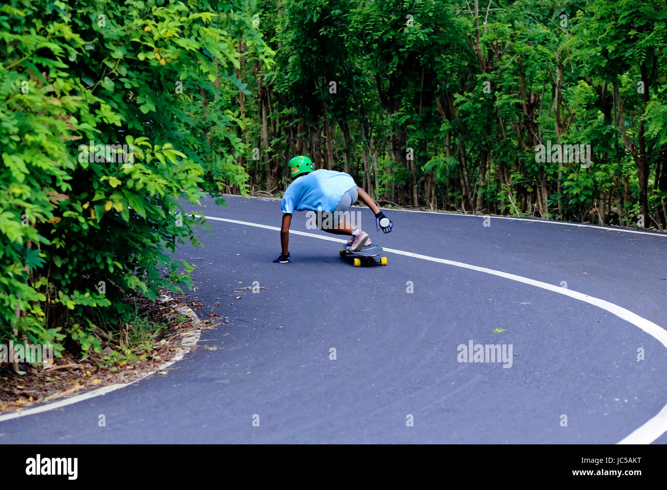 Longboarder staying low going around curve Stock Photo