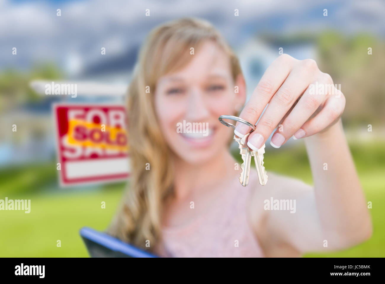 Excited Woman Holding House Keys and Sold Real Estate Sign in Front of ...