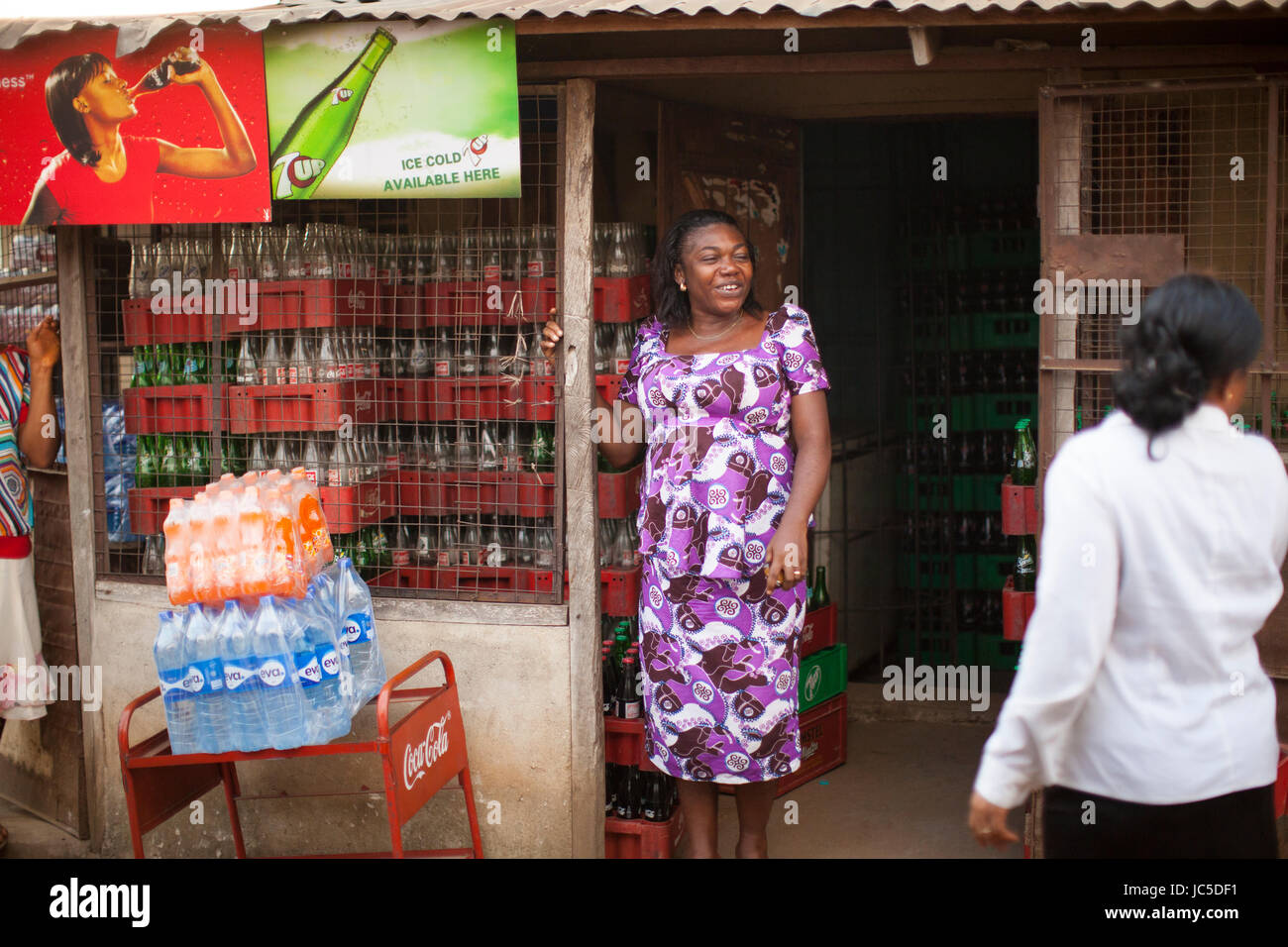 A female shop keeper in the doorway of her shop, Nigeria, Africa Stock Photo