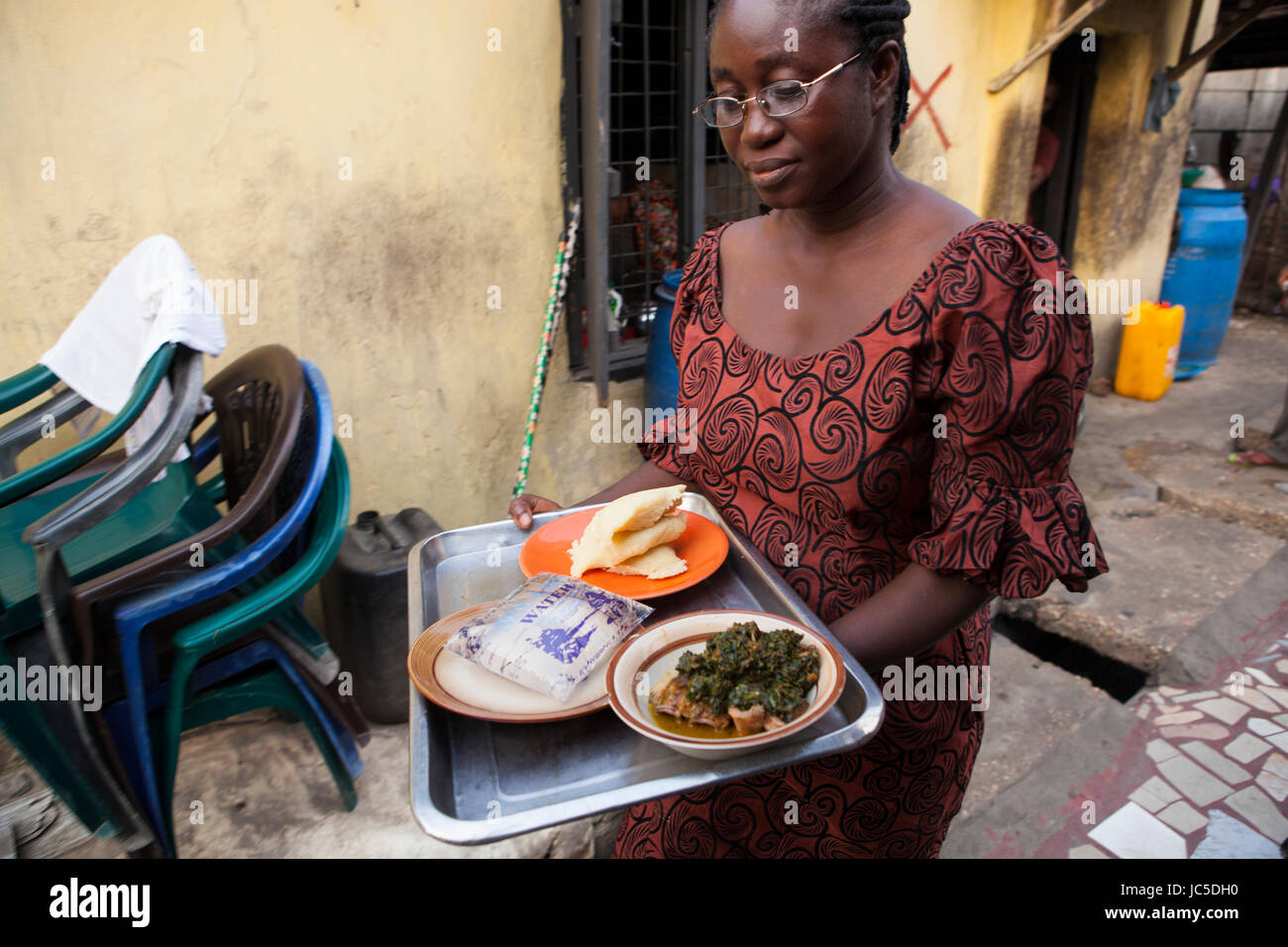 A woman carrying a tray of food and water, Nigeria, Africa Stock Photo