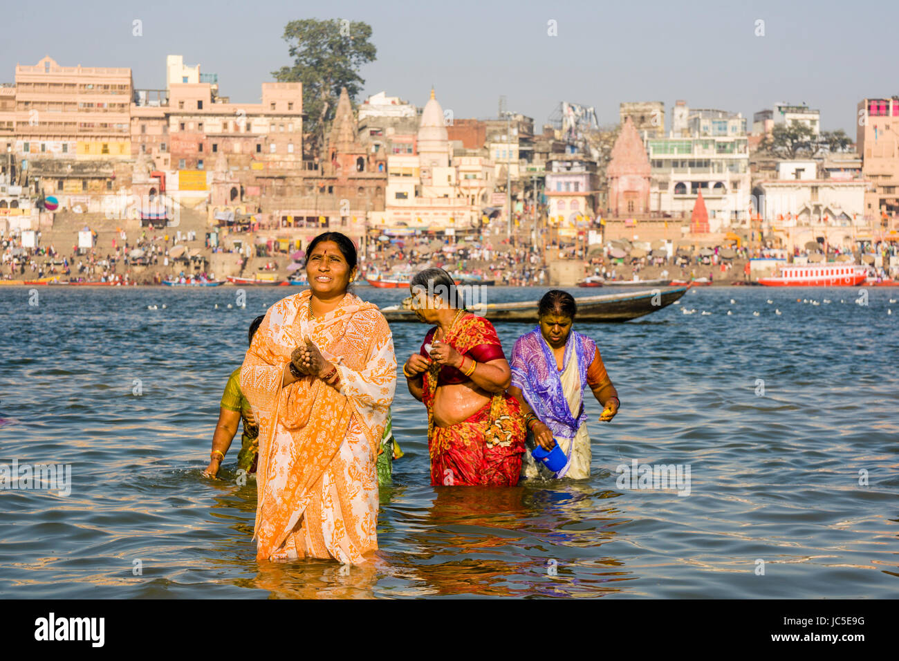Pilgrims are taking bath and pray on the sand banks at the holy river Ganges, panorama of Dashashwamedh Ghat, Main Ghat, in the distance Stock Photo