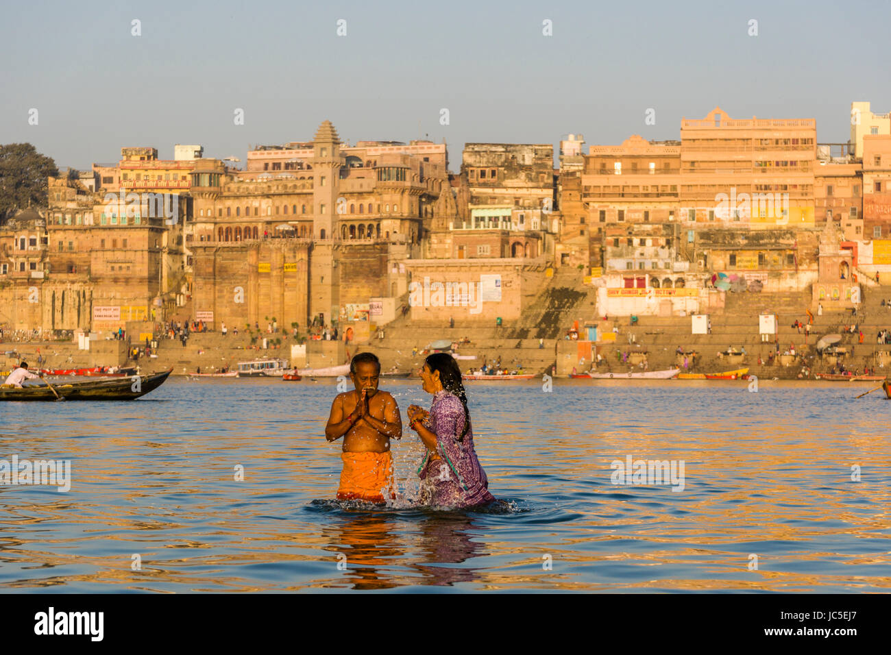 Pilgrims are taking bath and pray on the sand banks at the holy river Ganges, panorama of Dashashwamedh Ghat, Main Ghat, in the distance Stock Photo