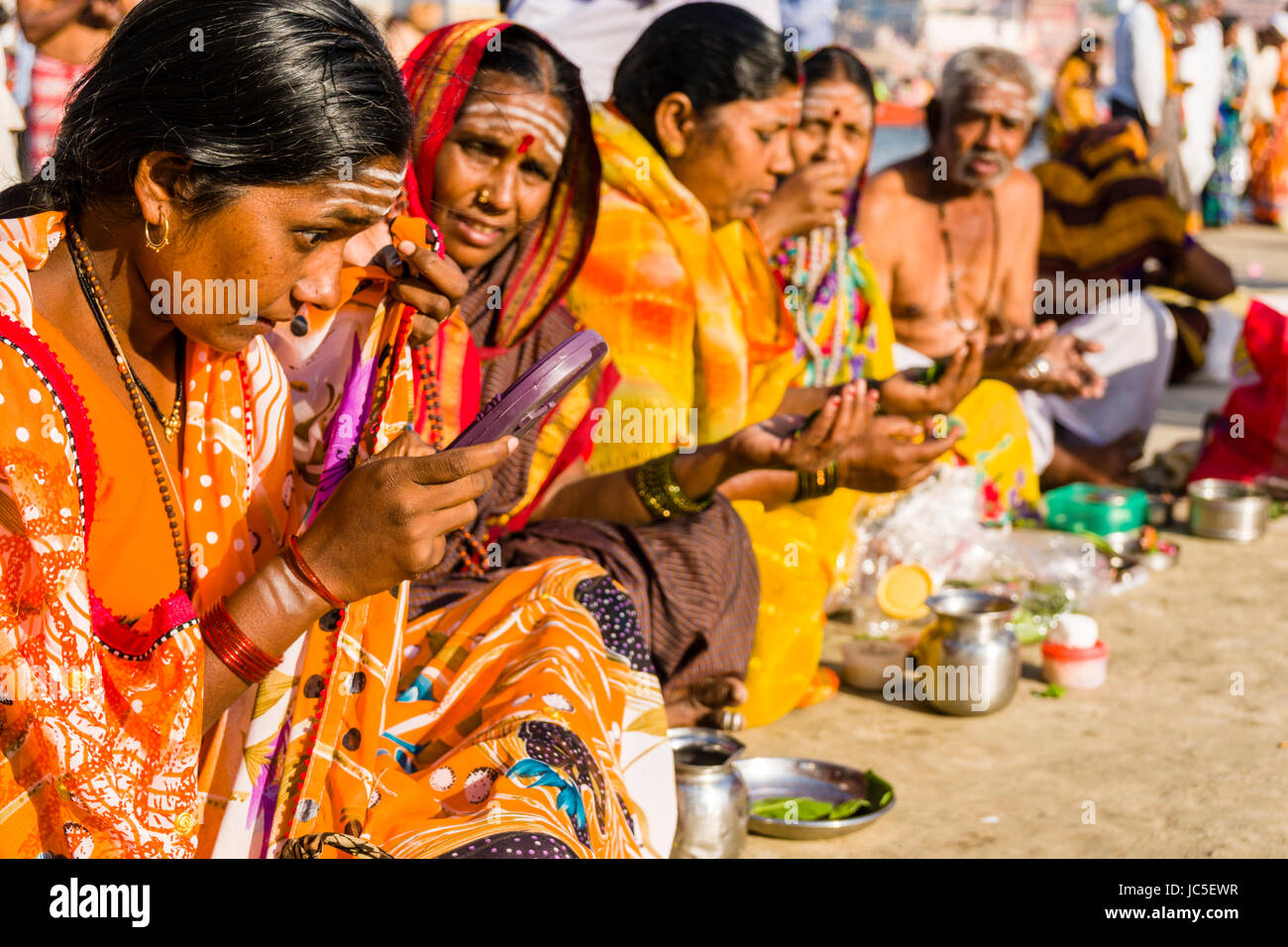 A group of female pilgrims is performing a religious ritual on the sand banks at the holy river Ganges Stock Photo