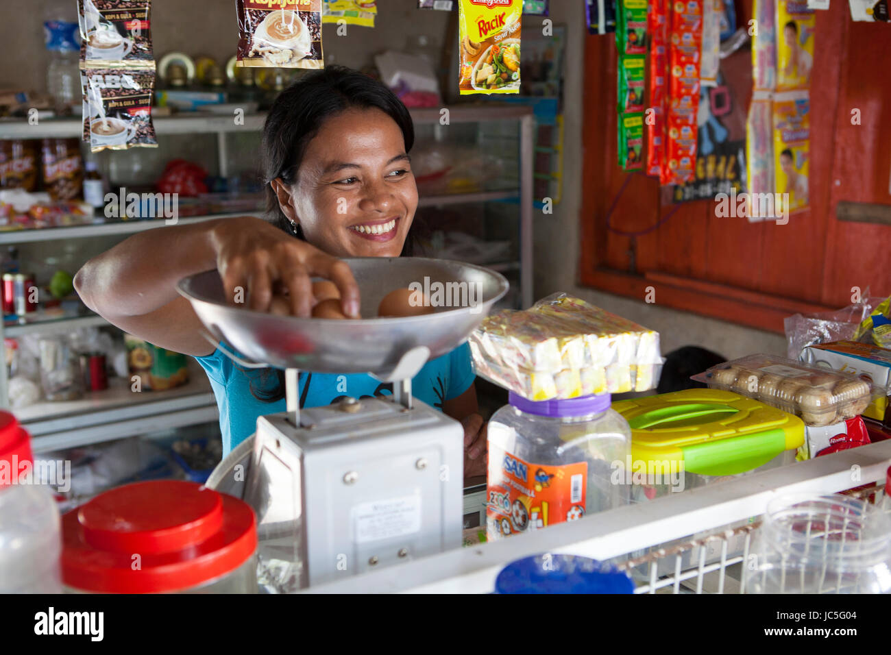 Jula Eha serving a customer in her shop outside the front of her house in a quiet residential area near the town of Bogor, Indonesia.  Her shop had mi Stock Photo