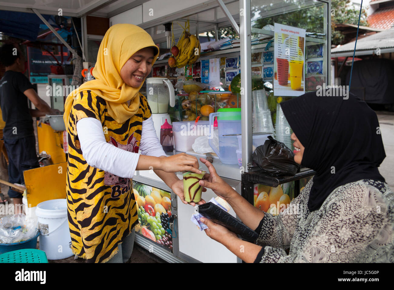 A women serving a fruit smoothie to a customer, Indonesia, Asia. Stock Photo
