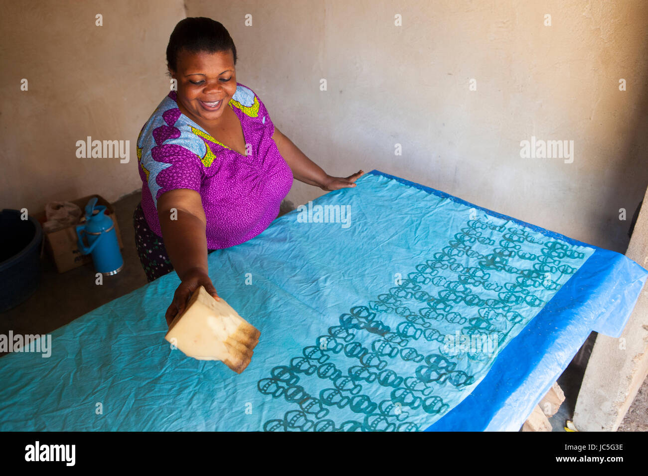 A female small business owner making a batik in her shop, Tanzania, Africa. Stock Photo