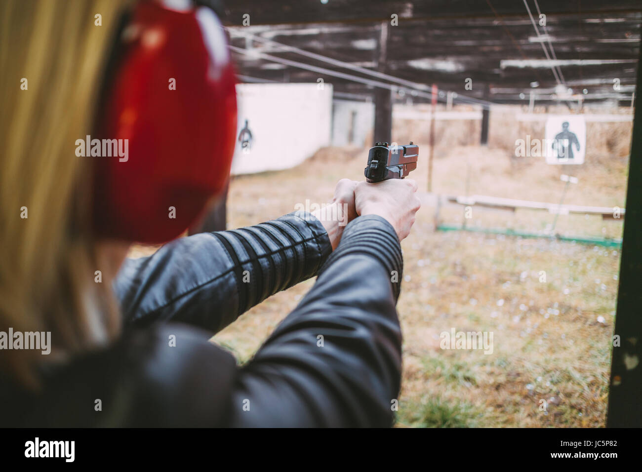 Woman firing with pistol on target at the shooting range. Closeup