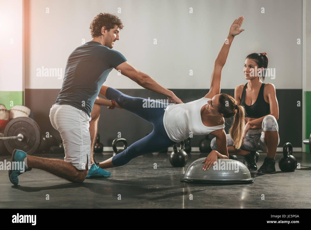 Two girl exercising at the gym with a personal trainer Stock Photo - Alamy