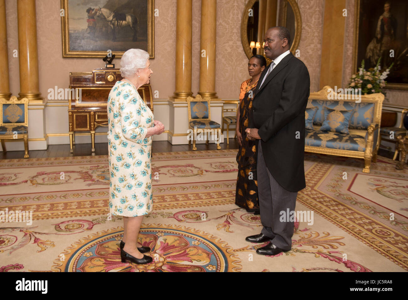 Queen Elizabeth II is presented with the Letters of Recall of his predecessor and his own Letters of Credence by His Excellency Ernest Ndabashinze, the Ambassador from the Republic of Burundi, as Mrs Maria Gloriose Kankindi looks on, during a private audience in Buckingham Palace, central London. Stock Photo