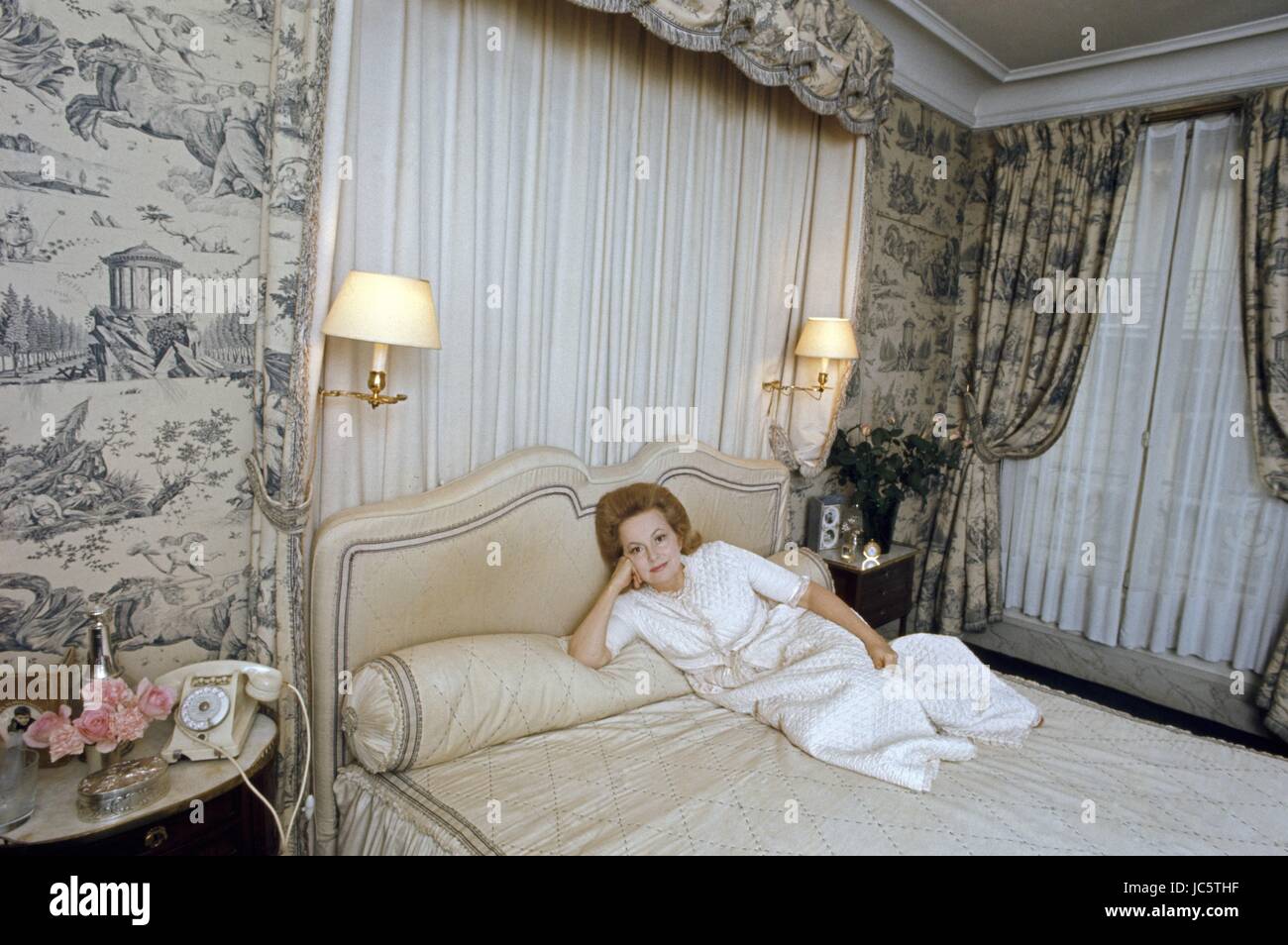 American actress Olivia de Havilland posing in the bedroom of her Paris