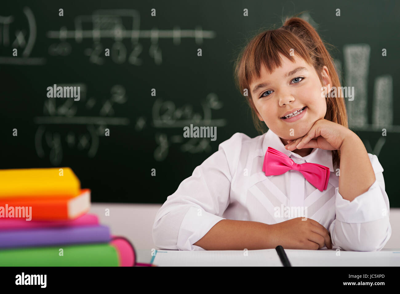 Cute little schoolgirl sitting in classroom with her books Stock Photo ...